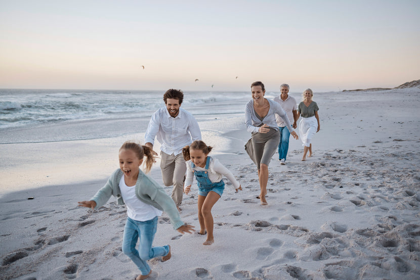 Großfamilie rennt lachend bei Sonnenuntergang am Strand